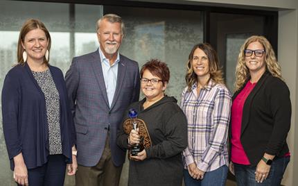 Kelly Thomas stands – silver and blue trophy in hand – between UFG’s Alison Kaster and Randy Ramlo on the left and nominators Vicky Wieditz and Erica Bergfeld-Reed on the right.