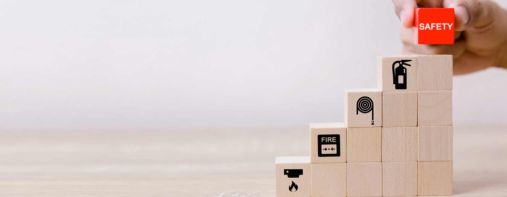 Stack of building blocks with hand placing one at the top that says Safety